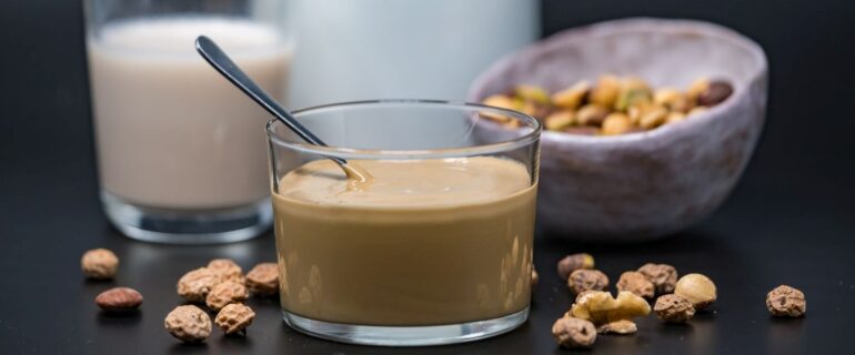 Tigernuts Butt3r, also known as Tigernut Cream, is a versatile and concentrated alternative for making plant-based tiger nut beverages in an easy and efficient way. 100% natural and made from organic tiger nuts, this product allows for the preparation of drinks with a very pleasant texture, a neutral flavor, and high physical stability. It is an ideal choice for both home and professional applications.
But what are the key factors to consider to get the best results when using Tigernuts Butt3r for making tiger nut drink?
Ideal Ratio: 1 part cream to 4 parts water
To achieve a drink with good body and a smooth texture, the recommended ratio is one part cream to every four parts water. This mixture produces a creamy drink, thanks to the natural starch content in the cream, which acts as a natural thickener and enhances the sensory experience with every sip.
Neutral flavor suitable for all palates
One of the most notable characteristics of Tigernuts Butt3r is its mild and neutral flavor, which allows it to be incorporated into a wide variety of recipes or consumed directly as a plant-based beverage. Since it does not have a dominant taste, it easily adapts to different types of preparations and dietary preferences, making it suitable for those seeking healthy, allergen-free alternatives without compromising on taste.
Nutritional comparison: sugar-free tiger nut drink vs. diluted tiger nut cream
Below is a nutritional comparison per 100 ml between a sugar-free tiger nut drink and one made by diluting Tigernuts Butt3r (1:4 ratio). The data clearly shows the higher nutritional content of the second option, particularly in healthy fats, fiber, and energy:
Component	Sugar-Free Tigernut Drink	Diluted Tigernut Cream (1:4)
Total fats	3.0 g	7.2 g
Saturated fats	0.5 g	1.6 g
Carbohydrates	3.7 g	9.0 g
Natural sugars	2.7 g	3.0 g
Dietary fiber	0.4 g	1.8 g
Protein	0.5 g	0.8 g
Energy	44 kcal	113 kcal
This information makes the drink resulting from diluted tiger nut cream a more energy- and nutrient-dense option, particularly suitable for those seeking greater nutritional density in their plant-based beverages.
Proper mixing: use mixers starting at 600 rpm
To achieve a homogeneous mixture without residue, it is recommended to use a mixer or blender operating at a minimum of 600 revolutions per minute (rpm). This speed ensures that the cream dissolves completely in water, resulting in a smooth, lump-free drink with fully integrated components.
High stability after preparation
Once diluted, the tiger nut drink made with Tigernuts Butt3r shows excellent physical stability, meaning the liquid phases do not separate quickly, as is often the case with other plant-based drinks. This allows the drink to be stored refrigerated for a longer time without needing constant shaking, making it more practical for daily use.
Conclusion: efficiency, nutrition, and taste in one solution
Using Tigernuts Butt3r as the base for tiger nut plant-based drinks helps optimize the preparation process but most importantly ensures a better nutritional profile in the final product. Thanks to its neutral flavor, ease of dissolution, and long-lasting stability, this cream represents an innovative and practical solution for crafting plant-based drinks with high added value.
Its use is especially recommended in settings where speed, consistency, and nutritional quality are required—such as coffee shops, artisan workshops, hospitality venues, or small-scale production.